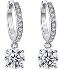 A pair of sterling silver huggie hoop earrings with a row of small clear stones and a large round clear gemstone dangling below, shown on a white background with inset quality marks.