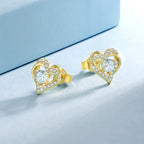 Pair of 14K gold plated heart moissanite studs on a pale blue background